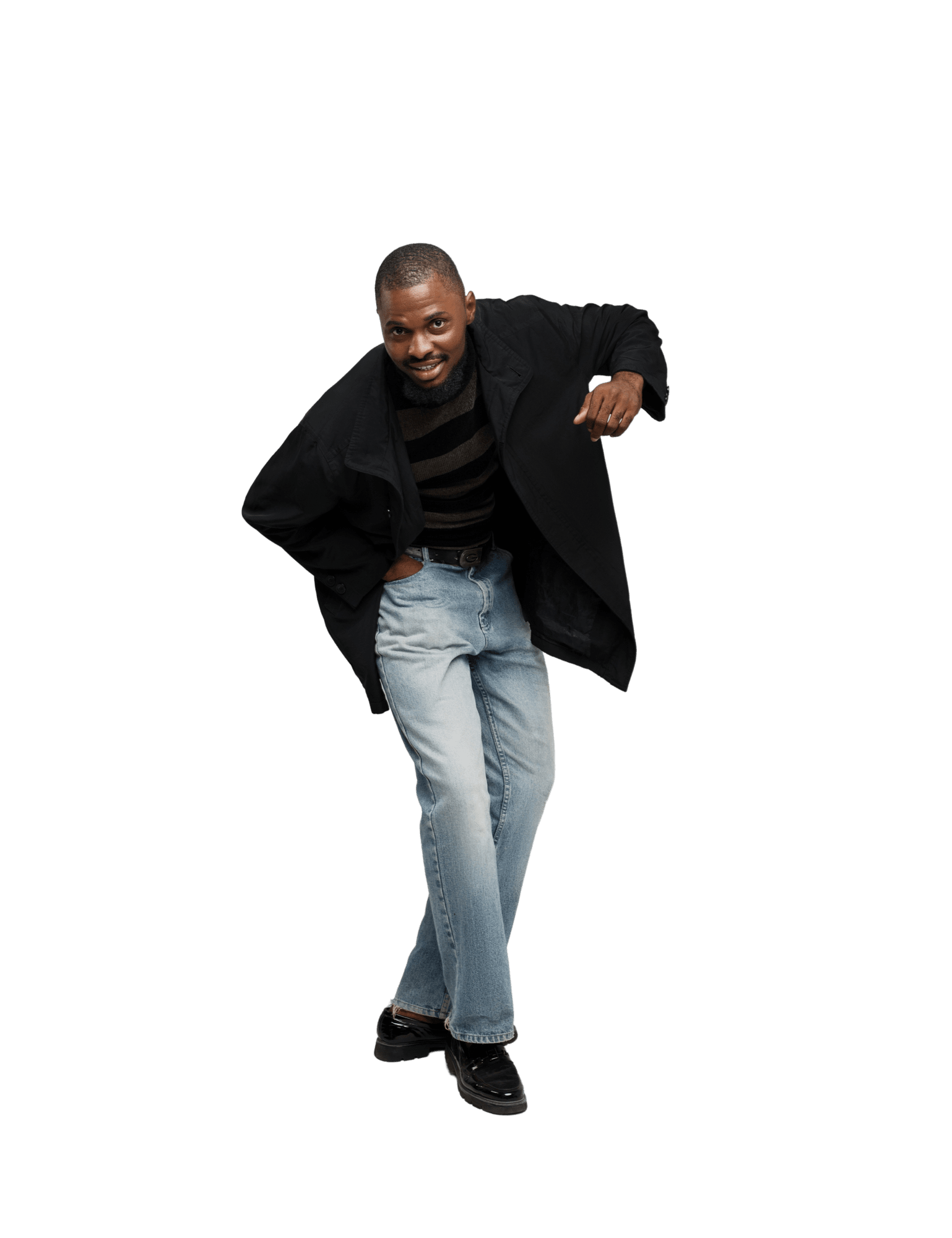 A smiling Black man wearing a black coat, striped shirt, and jeans leans forward playfully against a plain white background